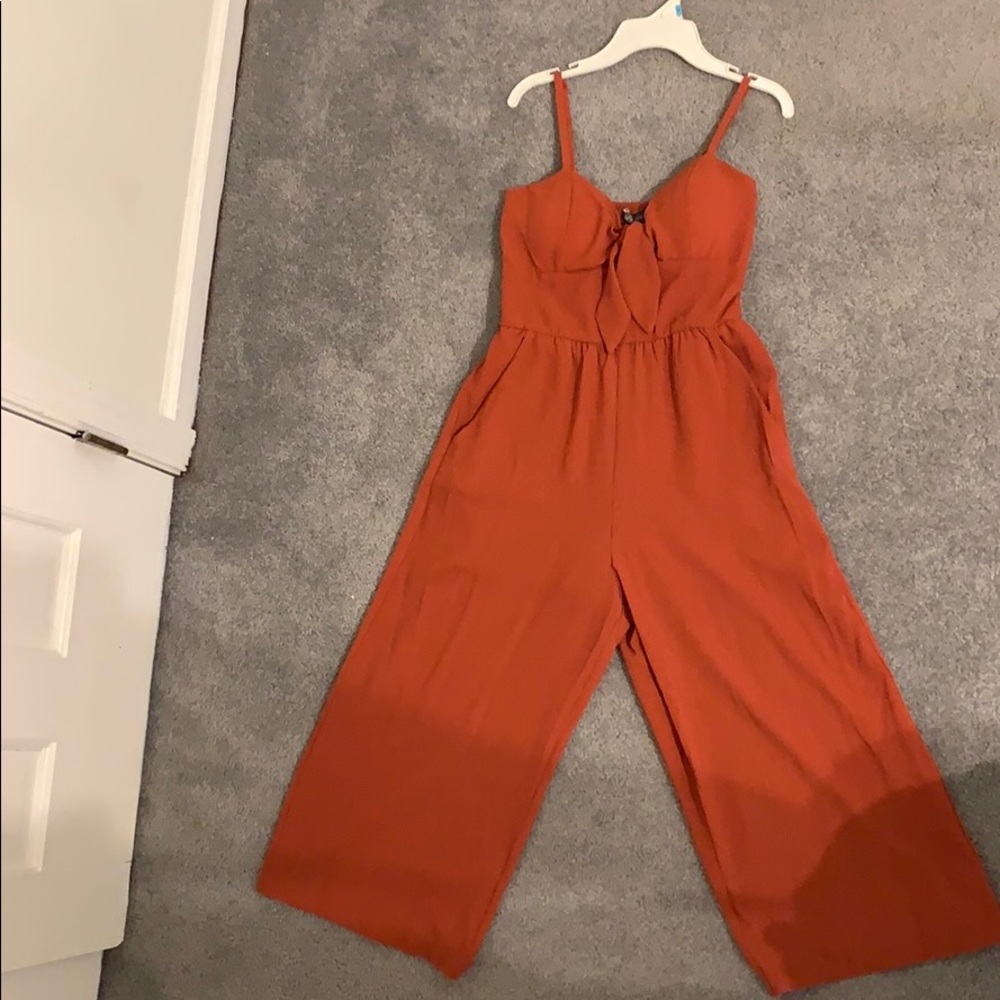 rust colored jumpsuit. flowy pants with pockets